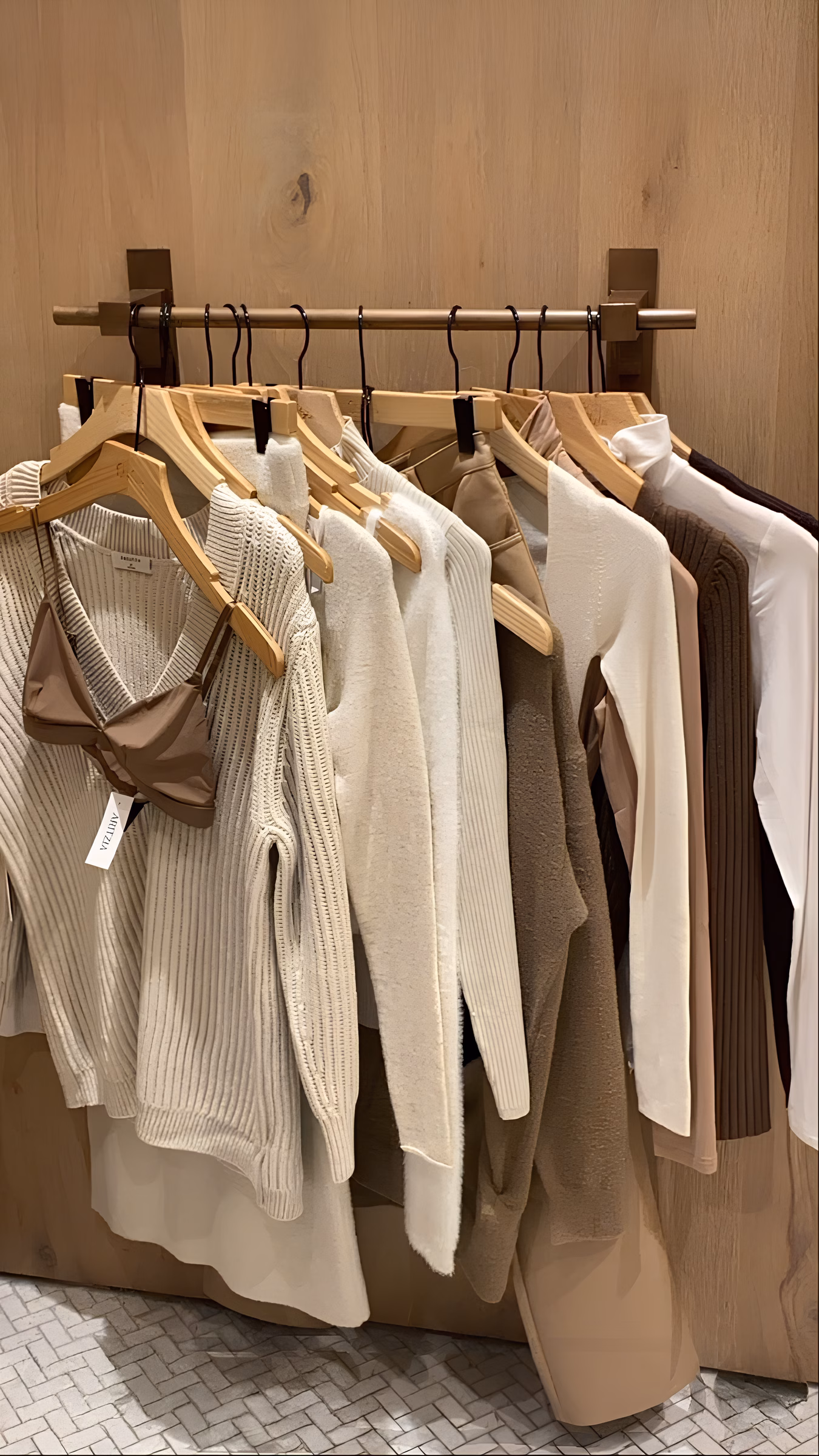 Neutral-toned luxury knitwear, blouses, and tailored layers on wooden hangers—a foundation for building an iconic capsule wardrobe