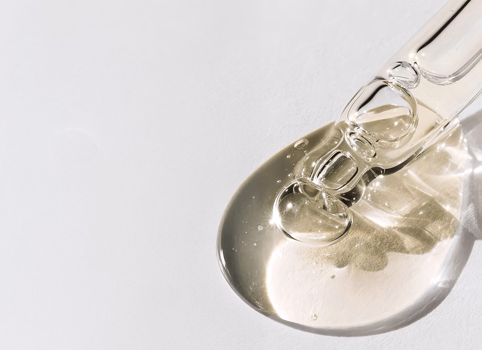 Clear serum with visible texture and bubbles on a white surface, photographed in soft natural light